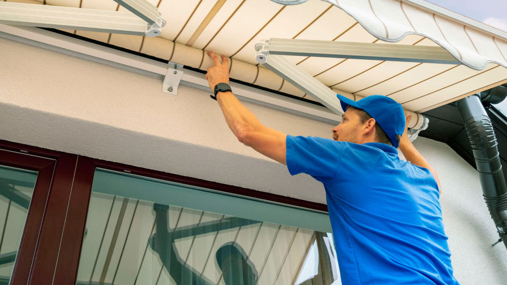 Dos personas instalando estructura de toldo en fachada residencial
